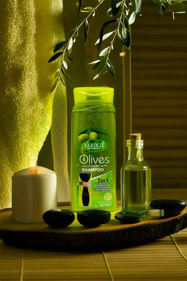 Bottle of Yardley Olives shampoo and conditioner on a wooden tray with a candle and stones.