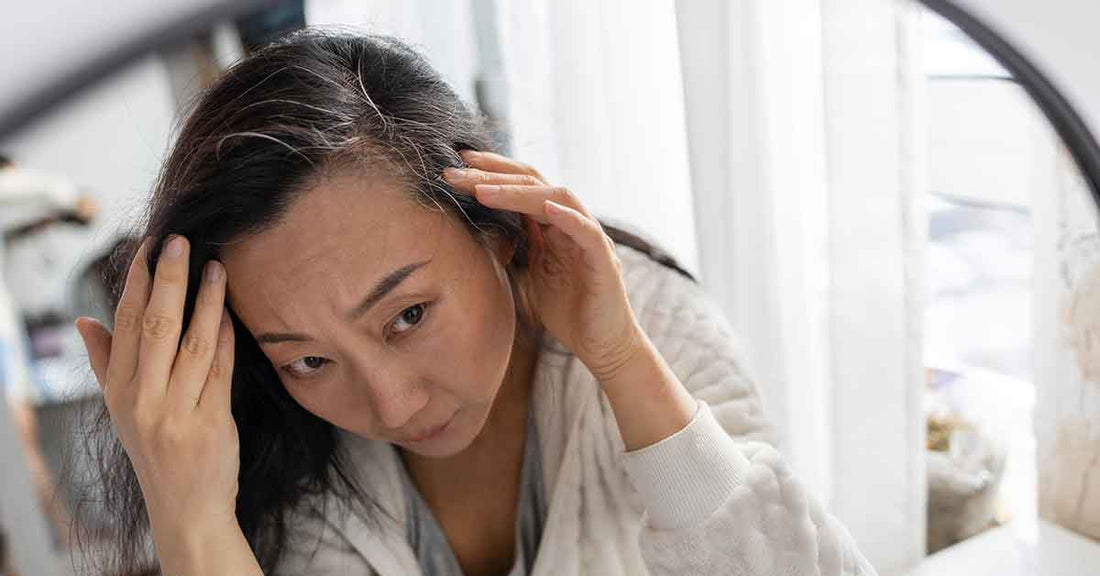 Woman checking grey hair roots in the mirror before using hair dye shampoo