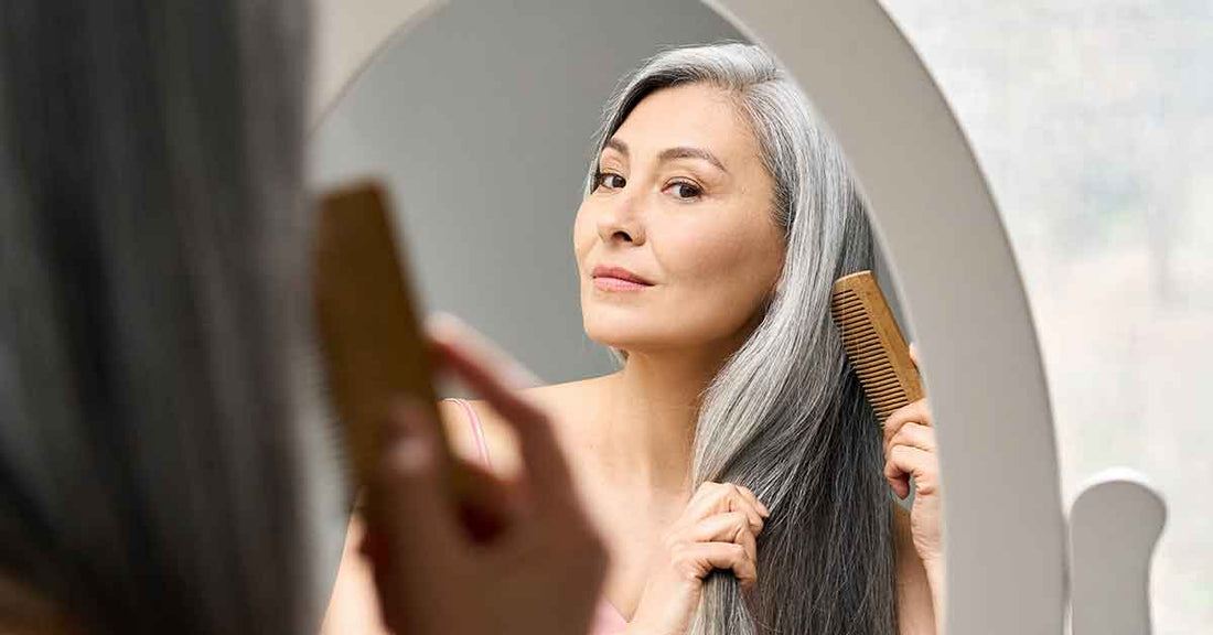 Woman checking grey hair in mirror before using hair dye shampoo for safe grey coverage