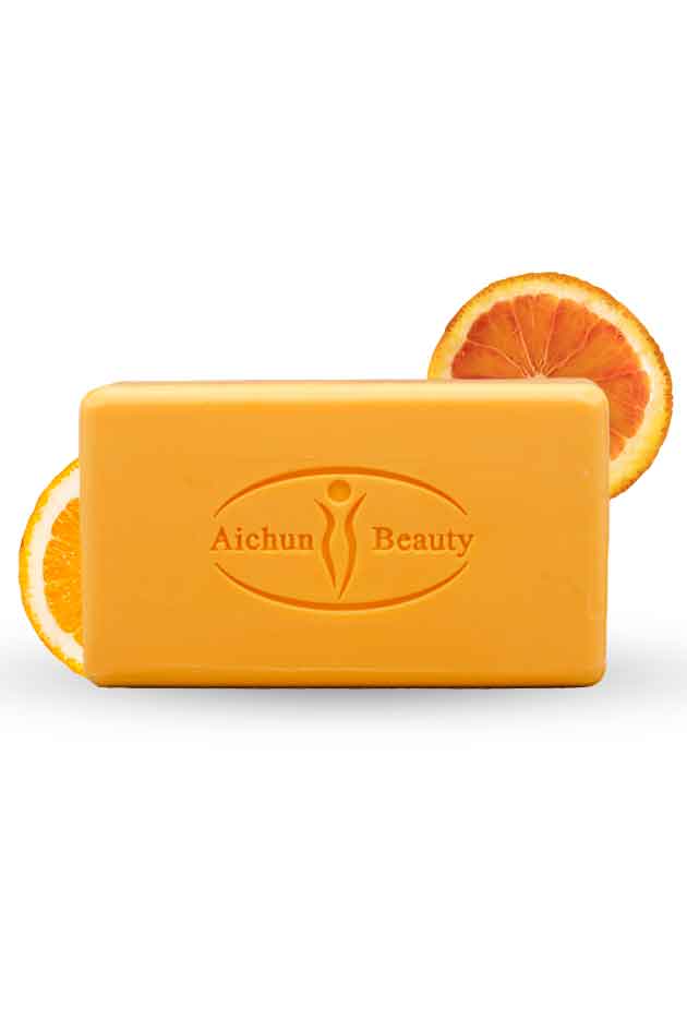 Aichun Beauty Vitamin C Soap – Super Whitening Multi-Purpose Face and Body Bar with Orange Extract. Orange bar of soap with 'Aichun Beauty' branding, surrounded by orange slices on a white background.