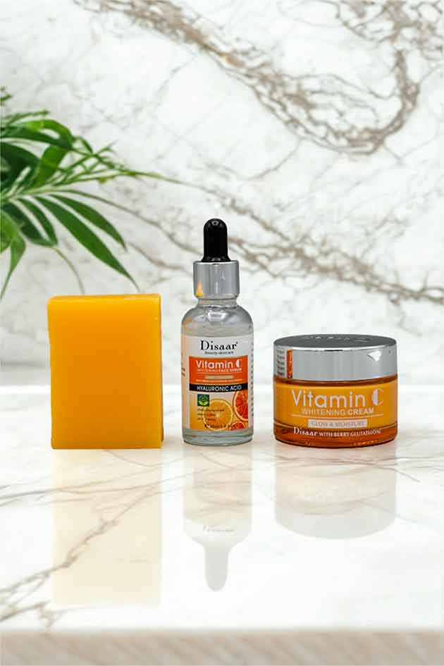 Disaar 3 in 1 Vitamin C Beauty Kit with Whitening Cream, Face Serum and Vitamin C Soap for Glowing Skin. Skincare products including a dropper bottle, cream jar, and soap bar on a marble surface with a plant in the background.