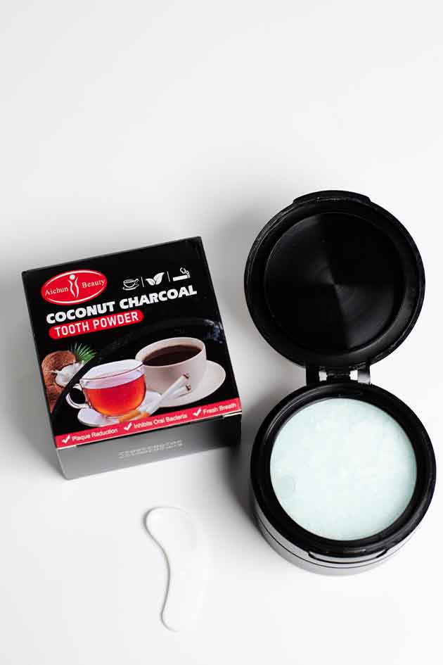 Coconut charcoal tooth powder packaging with a black container on a white background