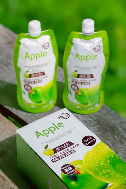 Two green apple juice pouches and a box on a stone surface with a blurred green background.