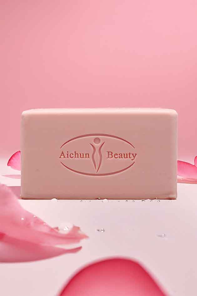 Bar of soap with 'Aichun Beauty' branding on a pink background with rose petals.