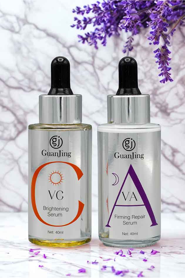Two skincare serum bottles with droppers on a light background with purple flowers.