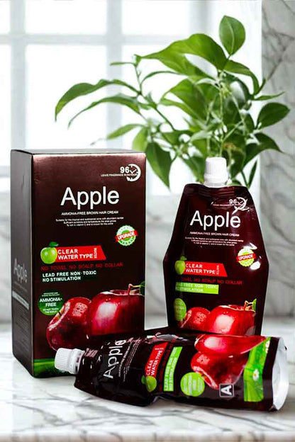 Apple hair care product packaging on a marble surface with a plant in the background