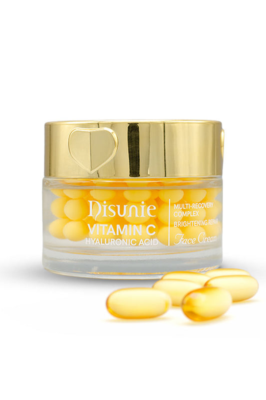 Disunie Vitamin C Hyaluronic Acid Face Cream 70g pack front,
A clear cosmetic jar labeled 'Disunie Vitamin C Brightening Cream' filled with yellow capsules, topped with a reflective gold lid, with several loose yellow capsules in front on a white background.