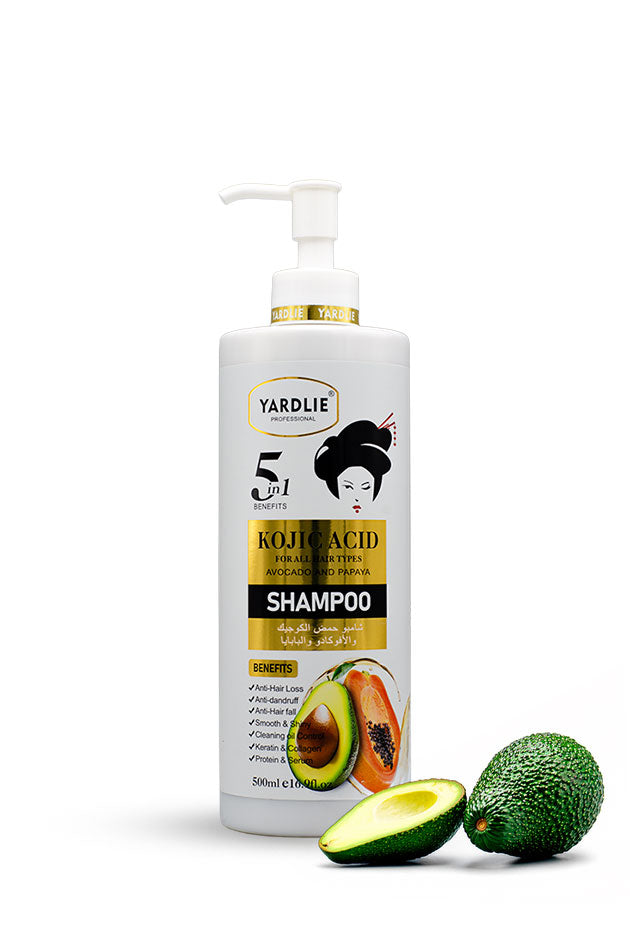 Yardlie Kojic Acid Avocado and Papaya Shampoo 500ml pack front,
A 500ml bottle of Yardlie Koujic Acid Scalp Treatment Shampoo, featuring a white pump dispenser and label with gold accents, avocado illustrations, and two whole and sliced avocados placed in front on a white background.