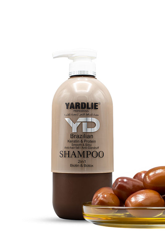 Yardlie Professional Brazilian Keratin and Protein 2 in 1 Shampoo with Biotin 800ml box and bottle,
A bottle of Yardlie Professional Brazilian Kermatin & Protein Shampoo, featuring a beige and brown gradient label with a white pump dispenser, set against a white background with a small glass dish of Brazilian palm nuts in the foreground.